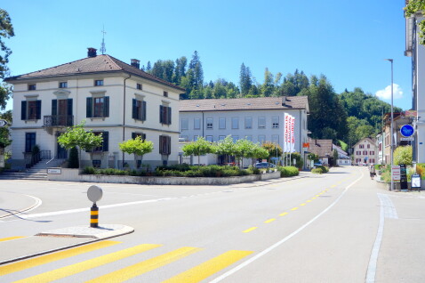 Die Einfahrt dazu liegt auf der Höhe Heinrich Gujerstrasse 10, gegenüber des Bahnhofs. An der Hauptachse, mitten durchs Dorf.